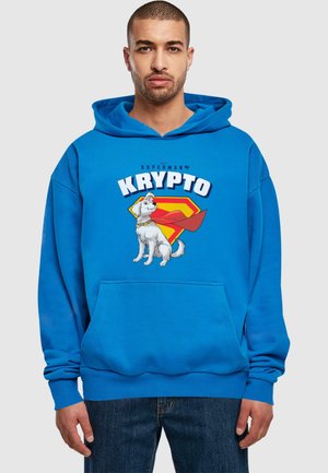 Blå hoodie med et grafik af en hvid hund med en rød kappe, teksten "SUPERMAN’S KRYPTO," og en kængurulomme.