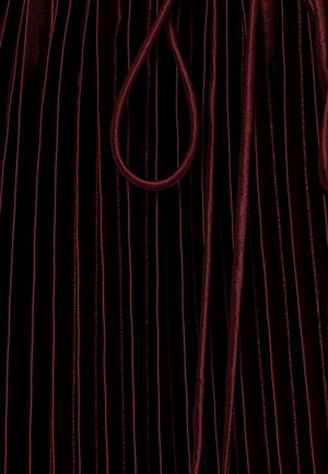 Tief burgunderroter Samtstoff mit vertikalen Falten und passenden dicken Kordeln, die locker auf der Oberfläche liegen.
