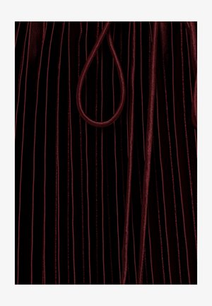 Tief burgunderroter Samtstoff mit vertikalen Falten und passenden dicken Kordeln, die locker auf der Oberfläche liegen.