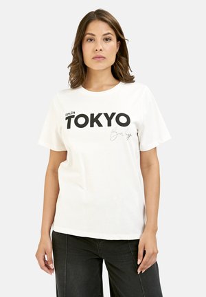 White cotton t-shirt with short sleeves featuring bold black text "I'm in TOKYO" and a cursive detail below. Simple, relaxed fit.