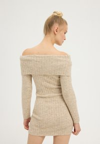 Abito in maglia off-the-shoulder color beige chiaro, con texture a costine e maniche lunghe, vita aderente e orlo corto. Finitura in tessuto morbido.