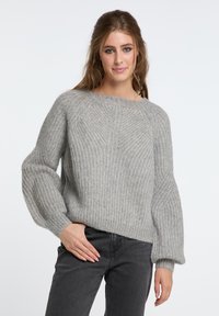 Grauer gestrickter Pullover mit einem strukturierten Rippenmuster, rundem Halsauschnitt und ballonförmigen Ärmeln, kombiniert mit grauen Jeans. Weiches und zeitgenössisches Design.