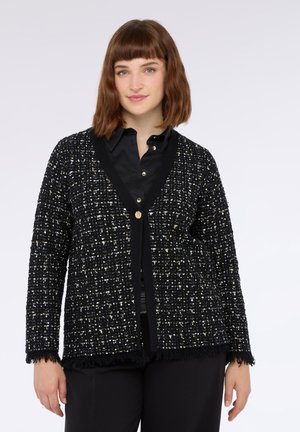 Schwarze Strickjacke mit einem strukturierten Muster aus metallischen Fäden. V-Ausschnitt-Design, eine Knopfverschluss und fransige Saumakzente.
