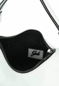 Bolso de piel blanco con cierre de cremallera, que cuenta con un forro de tela negra y un pequeño bolsillo interior con cremallera. Etiqueta del logo visible en el interior.