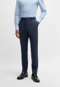 Navy blue tailored trousers with a textured finish, featuring a flat front, belt loops, and a slim fit, paired with black dress shoes.