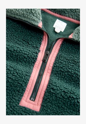 Green fleece pullover with a high collar, featuring a contrasting pink zipper and trim, textured surface, and a tag visible near the collar.