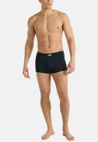 Svarta boxershorts i stretchmaterial med en åtsittande design och en kontrasterande vit logotyp på midjebandet. Mjuk textur och medellång benlängd.