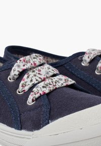 Jūros mėlynos drobės sportbačiai su gėlių raštų raišteliais, baltais gumos pado ir kontrastingais siūlais palei kraštus.