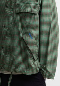 Πράσινο και καφέ μικρό καρό σακάκι με τσεπάκι με καπάκι και κουμπιά κλικ στο μπροστινό μέρος, με το λογότυπο Barbour στο καπάκι της τσέπης.