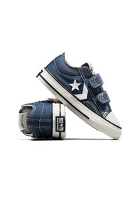 Blaue Denim-Sneaker mit weißem Stern-Logo, zwei Klettverschlüssen, weißer Gummikappe und schwarzer Sohlenverzierung. Mit weißen kontrastierenden Nähten.