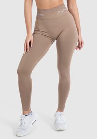 Beige legging met een hoge elastische tailleband met het "SMIL" logo. Gemaakt van rekbaar, soepel materiaal voor comfort en flexibiliteit.