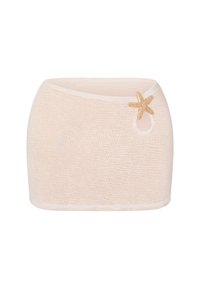 Jupe mini texturée beige avec une taille asymétrique et un accent décoratif en étoile de mer dorée près du coin supérieur droit.