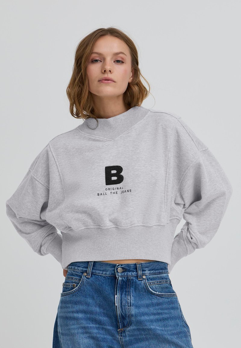 Sivý krátky sweatshirt s vysokým golierom, s čiernym logom "B" a textom "ORIGINAL BALL THE JEANS". Mäkko látka a uvoľnený strih.
