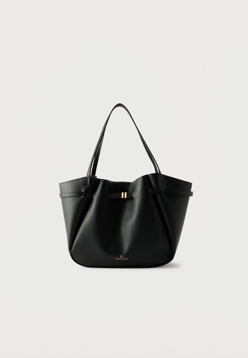 Sac cabas en cuir noir avec deux bretelles, un petit fermoir doré et le logo "Anna Field" sur fond blanc.