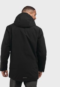Schwarze Kapuzenjacke mit schlankem Design, das eine glatte Textur und einen langen Schnitt aufweist, von hinten gesehen, mit minimalen Hardware-Details.
