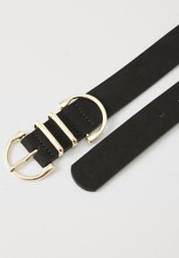 Ceinture en cuir noir avec une boucle en métal doré dotée de trois barres horizontales et d'un anneau circulaire. Texture lisse, design minimaliste.