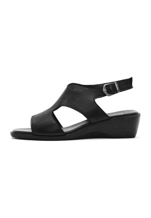 Sandalia cuña abierta con punta al descubierto de cuero negro, con laterales recortados y correa ajustable en el tobillo con hebilla plateada, mostrada de perfil sobre fondo blanco.