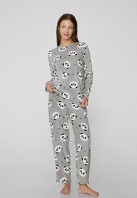 Conjunto de pijama gris de tela suave, con un patrón de pandas y acentos en blanco y negro. Top de manga larga combinado con pantalones a juego.