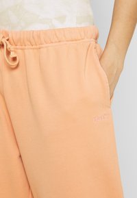 Perzikkleurige joggingbroek met een elastische tailleband, koord en zijzakken; met een roze geborduurd Levi's-logo.