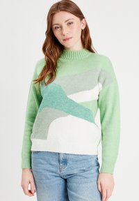 Strikket sweater i varierende nuancer af grøn med hvide og lysegrå abstrakte mønstre, med ribbede kanter ved halsen og håndleddene.