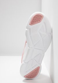 Buty sportowe z teksturowaną, białą gumową podeszwą z wzorem plastra miodu, różowymi akcentami i miękką, oddychającą cholewką.