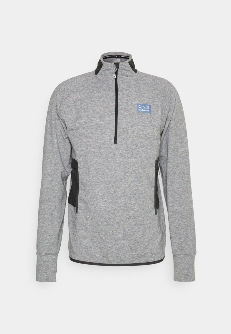 Sudadera deportiva de manga larga gris con cremallera en la parte delantera, bolsillos laterales negros y un pequeño logo azul de New Balance en el pecho.