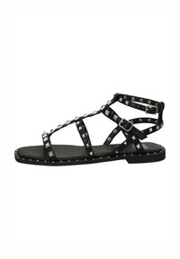 Sandal flat nera con decorazioni a borchie, caratterizzata da un design a lacci e una fibbia regolabile. Realizzata in pelle con una texture liscia.