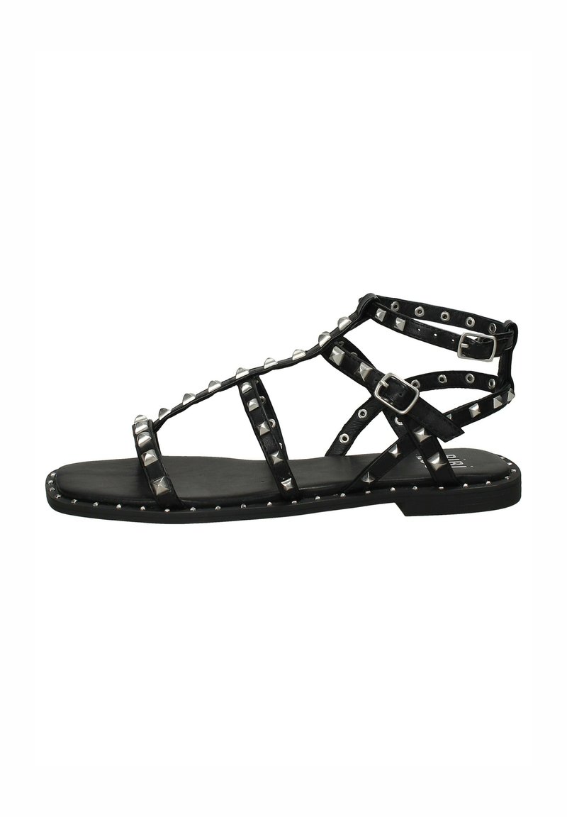 Sandal flat nera con decorazioni a borchie, caratterizzata da un design a lacci e una fibbia regolabile. Realizzata in pelle con una texture liscia.