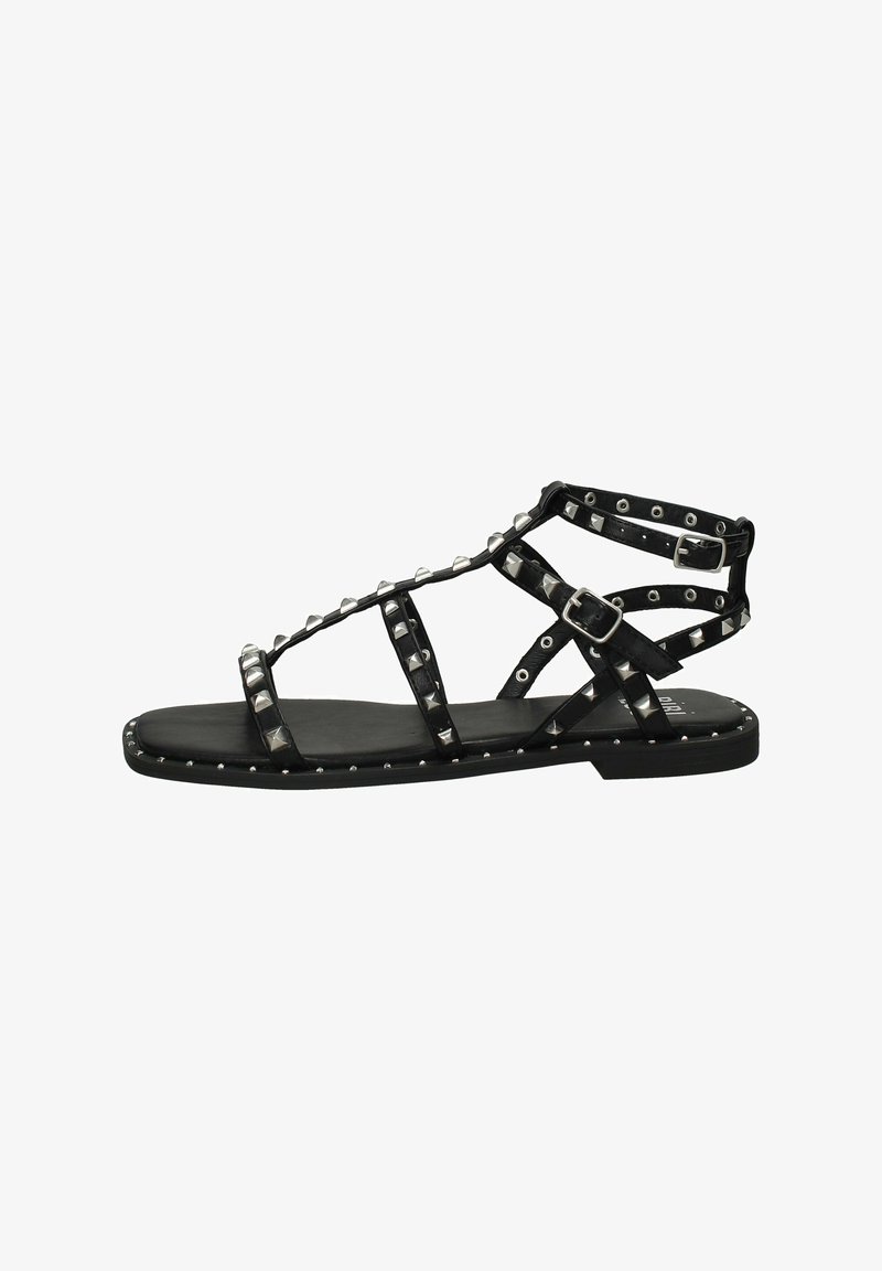 Sandal flat nera con decorazioni a borchie, caratterizzata da un design a lacci e una fibbia regolabile. Realizzata in pelle con una texture liscia.