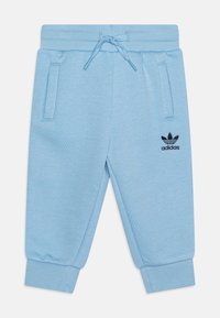 Svetlo modre bombažne trenirke z elastičnim pasom, vrvico, dvema stranskima žepoma in črnim vezenim logotipom Adidas na levi nogi.