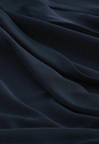 Marinblått tyg med en mjuk, slät yta som visar elegant fall och en lätt reflekterande finish. Inga mönster eller detaljer synliga.
