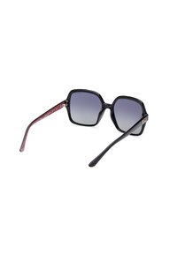 Occhiali da sole neri a forma ottagonale con lenti sfumate. Le astine interne texture rosse presentano un motivo. Design audace con finitura lucida.