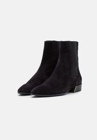 Bottines en suède violet foncé avec un bout pointu, des panneaux latéraux élastiques et un petit talon carré orné d'un accent métallique.