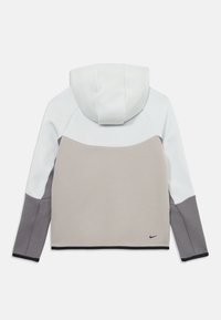 Hettegenser med fargeblokkdesign i hvitt, lys beige og mørk grå. Mykt stoff med en tettsittende passform og Nike-logo på nederste venstre side.