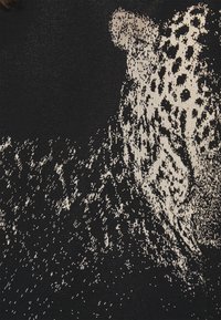 Dzianina o czarnym tle z abstrakcyjnym nadrukiem lamparta w kolorze kremowym, prezentująca różnorodne faktury i pikselowane wzory.