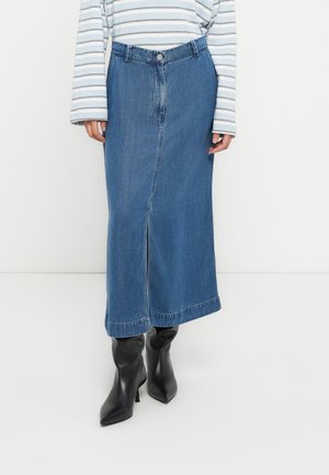 Jeanskjol i medelblå färg, knälång med en frontslits, bältesöglor och knäppning med knappar fram. Matchad med svarta boots med spetsig tå.