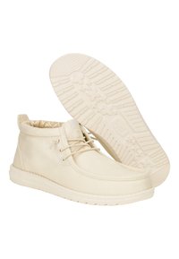 Botas de tobillo de lienzo beige con punta redonda, diseño de cordones y un interior estampado. La suela de goma presenta un diseño de tracción.