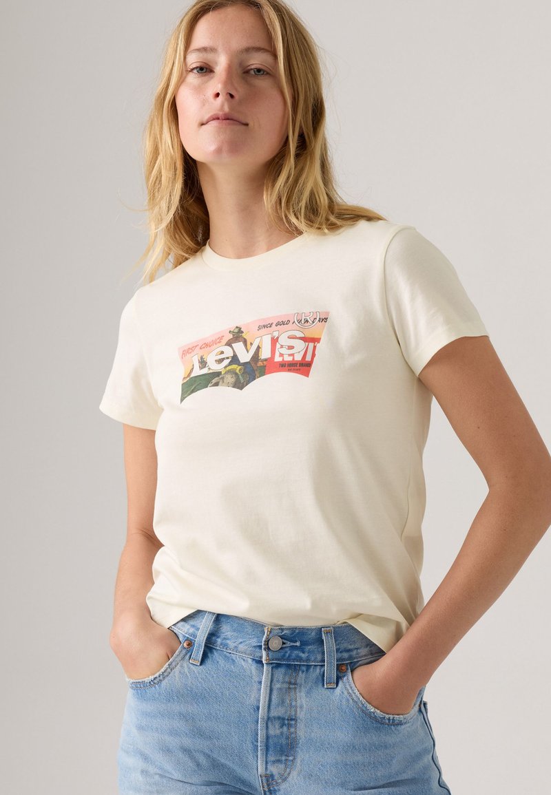Crème-kleurig katoenen t-shirt met een retro, kleurrijke Levi's logo-opdruk op de voorkant. Het heeft korte mouwen en een ronde hals.