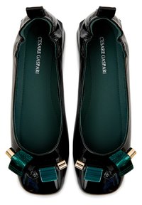 Ballerines en cuir verni noir ornées d'un accent géométrique vert et turquoise et de détails dorés sur le bout. Doublure intérieure en vert doux.