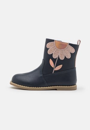 Stivaletti alla caviglia color navy in pelle liscia, caratterizzati da un'applicazione a forma di fiore rosa glitterato e una suola in gomma color cognac. Striscia posteriore per facilitare la calzata.