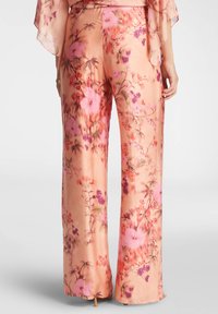 Pantaloni a gamba larga in satin morbido color pesco con stampa floreale. Presentano motivi di fiori rosa e viola, una texture fluente e una leggera svasatura all'orlo.