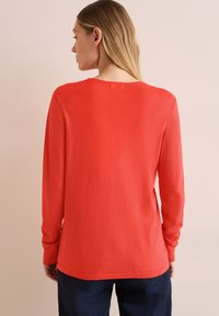 Roter Pullover mit langen Ärmeln und rundem Halsausschnitt, glatter Textur und gerippten Bündchen. Die Rückseite hat ein einfaches Design und einen geraden Saum.