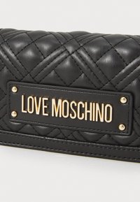 Juodas siuvinėtas odinis piniginė su auksiniu "LOVE MOSCHINO" logotipu ir aukso spalvos kalnų karoliukais. Dėlionės serijoje yra įstrižos siūlės.