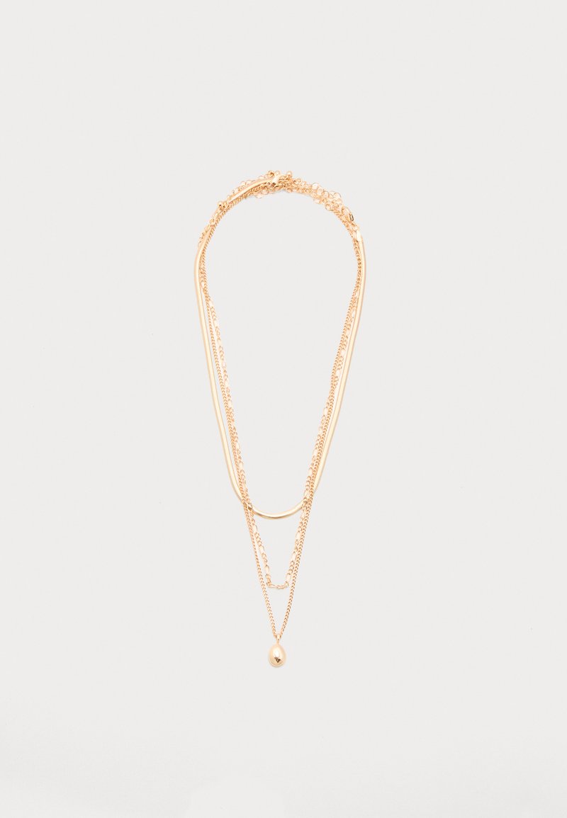 Κολιέ τριών στρωμάτων από χρυσό με λεπτές αλυσίδες, μια καμπυλωτή μπάρα και ένα μικρό οβάλ μενταγιόν στην πιο μακριά αλυσίδα, παρουσιάζεται σε λευκό φόντο.