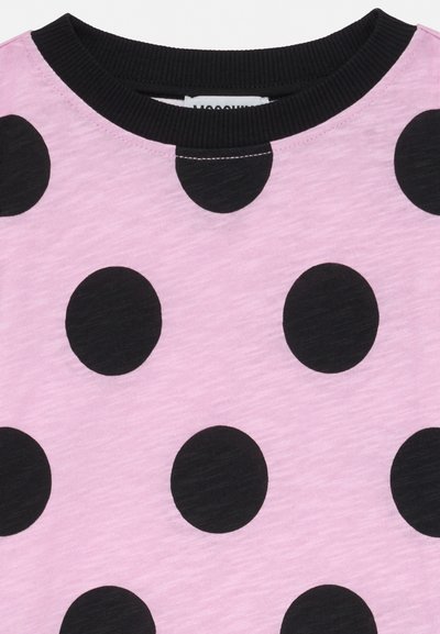 Różowa tkanina z dużymi czarnymi kropkami w groszki i prążkowanym czarnym okrągłym dekoltem.