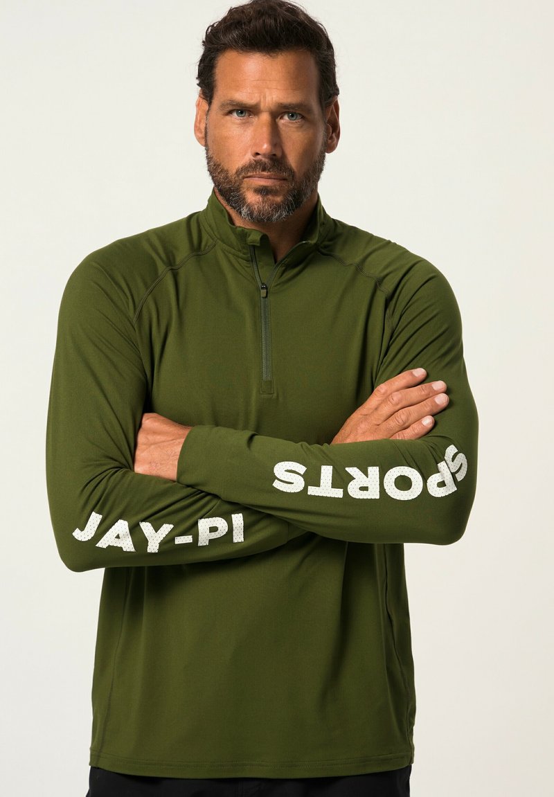 Maglietta sportiva verde con zip e maniche lunghe, caratterizzata da testo stampato bianco "JAY-PI" e "SPORTS" lungo le maniche, texture liscia.