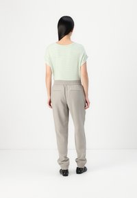 T-shirt rayé vert clair à manches courtes retroussées, associé à un pantalon gris clair à taille élastique. Les pantalons comportent des poches latérales et des poches à chevilles cintrées.
