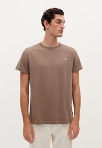 Korte bruine t-shirt met korte mouwen in zachte stof, met een ronde halslijn en een klein logo detail op de borst.
