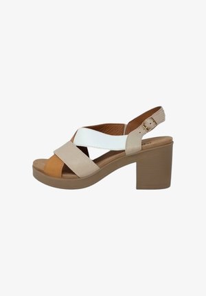 Sandali con tacco caratterizzati da cinturini incrociati in pelle beige, bianca e marrone, con un robusto tacco a blocco e una chiusura a fibbia sul cinturino posteriore.