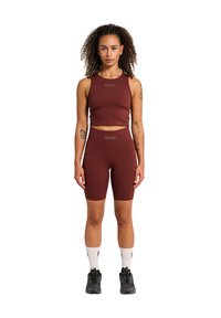 Burgundy sportig crop top och shorts-set med "HALO"-logotyp. Materialet är slätt, passformen är åtsittande. Modellen bär svarta sneakers och vita strumpor.